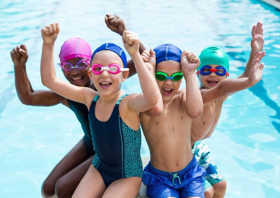 Portrait of cheerful children enjoying at poolside